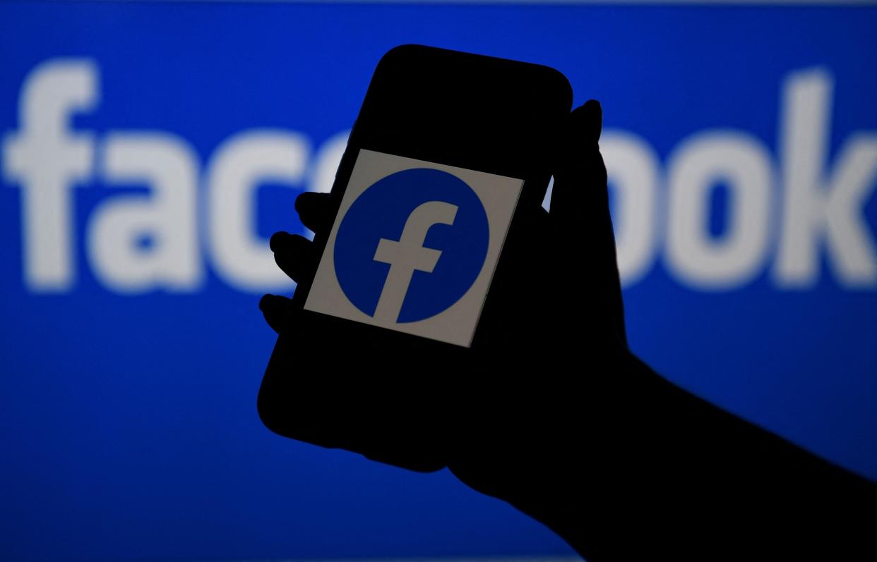 In this file photo illustration, a smart phone screen displays the logo of Facebook on a Facebook website background.