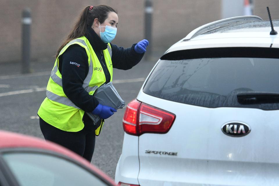 A Serco worker passes coronavirus test kits to members of the public arriving at a temporary COVID-19 testing facility at the Walsall Arena & Arts Centre in Walsall, central England. Photo: Oli Scarff/AFP via Getty Images