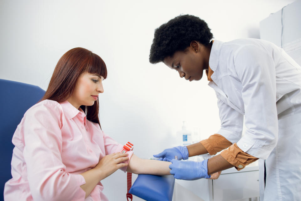 Healthcare worker preparing to draw blood from patient's arm in medical setting