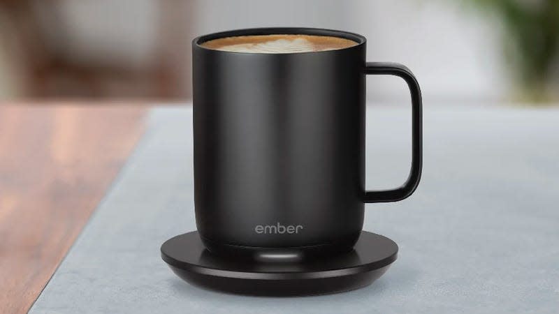 The Ember self-heating mug on its charging base sitting on a desk.