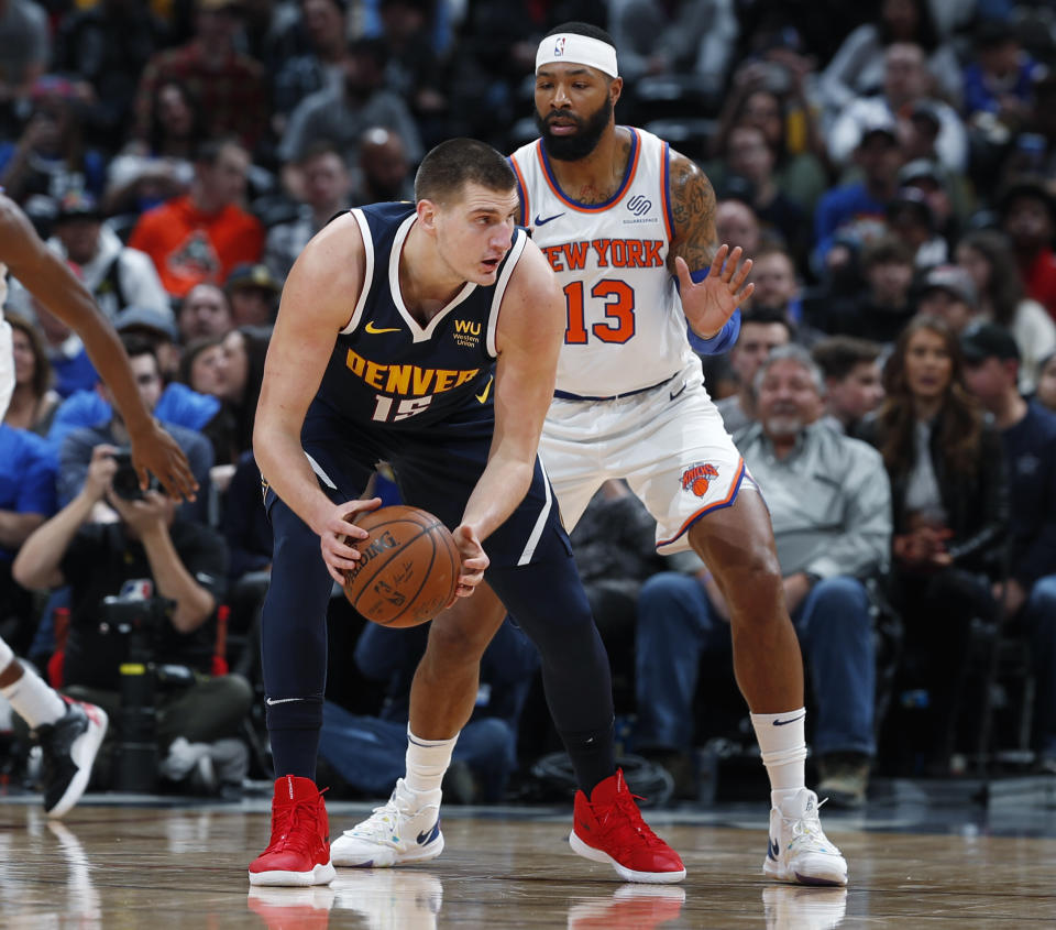 Denver Nuggets center Nikola Jokic, left, looks to pass the ball as New York Knicks forward Marcus Morris Sr. defends in the first half of an NBA basketball game Sunday, Dec. 15, 2019, in Denver. (AP Photo/David Zalubowski)