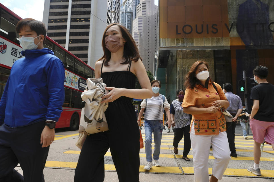 People wearing face masks to prevent the spread of coronavirus walk on a downtown street in Hong Kong, Tuesday, Aug. 17, 2021. Hong Kong will tighten entry restrictions for travelers arriving from the United States and 14 other countries from Friday, increasing the quarantine period to 21 days. (AP Photo/Vincent Yu)