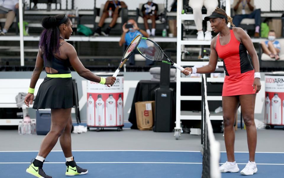 Serena Williams (L) and Venus Williams touch rackets  - Getty Images