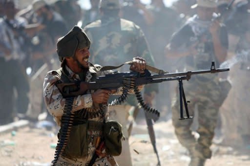 Libyan National Transitional Council (NTC) fighters fire at forces loyal to Moamer Kadhafi during battles in Sirte. Libyan fighters raised the new government's flag over the oasis of Bani Walid Monday and hoped for the swift fall of the other remaining redoubt of Kadhafi loyalists, Sirte, as relatives of his henchmen fled