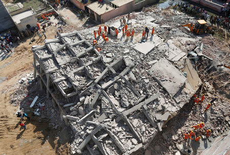 Rescue workers look for survivors amidst the rubble at the site of a collapsed residential building at Shah Beri village in Greater Noida, July 18, 2018. REUTERS/Adnan Abidi