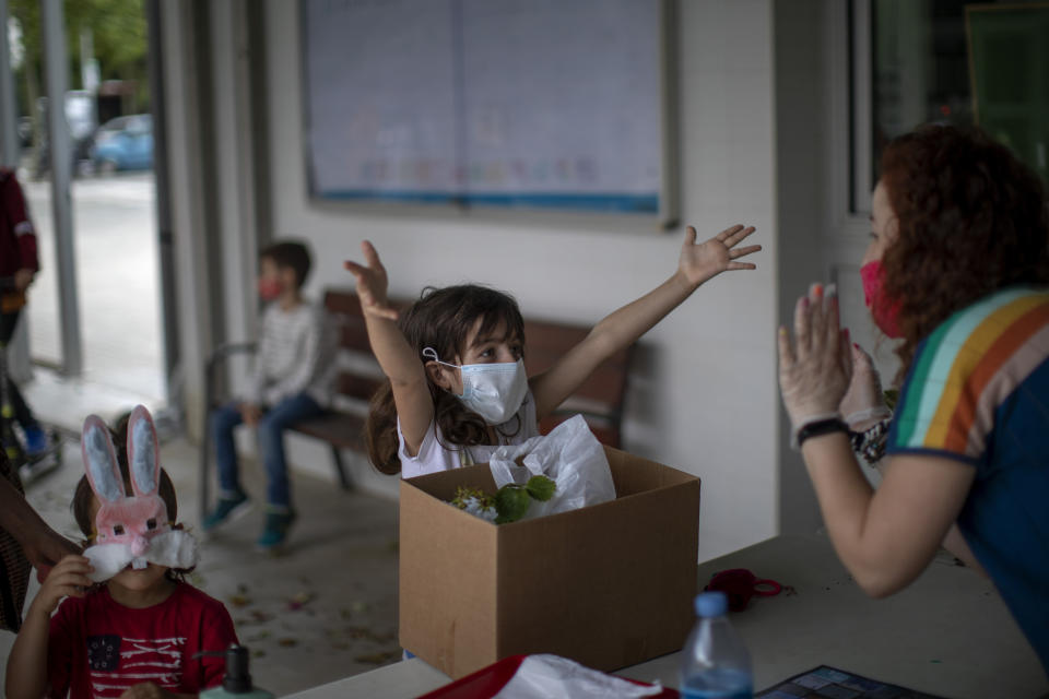 A primary school student gestures as if asking for a hug from her teacher at the end of the school year in Barcelona.  (Photo: AP Photo/Emilio Morenatti)