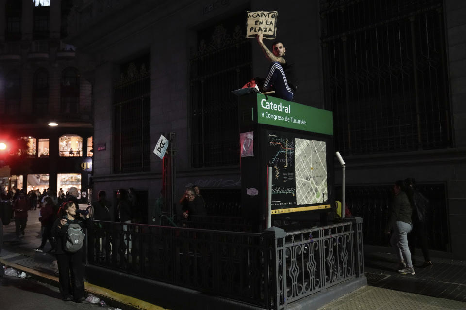 A protester sits atop a subway entrance during a march demanding more funding for public universities and protest against austerity measures proposed by President Javier Milei in Buenos Aires, Argentina, Tuesday, April 23, 2024.(AP Photo/Rodrigo Abd)