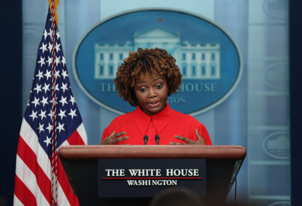 Karine Jean-Pierre at the podium in the White House press briefing room.