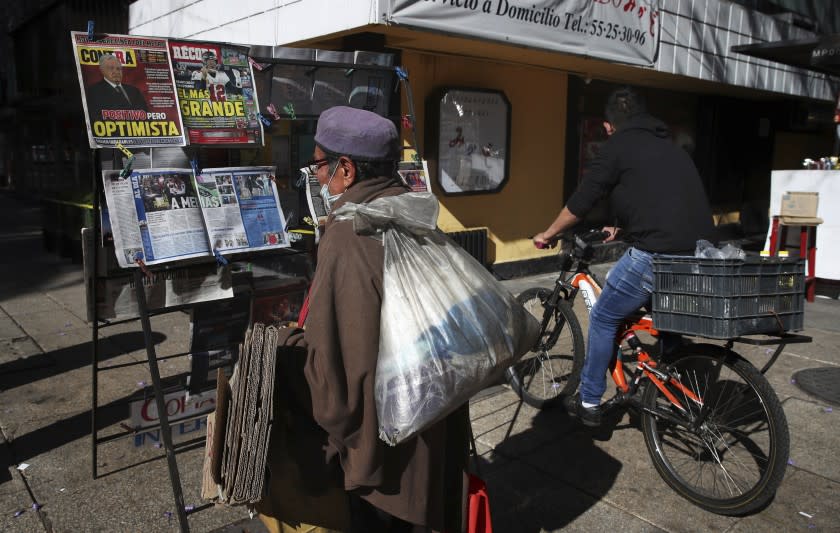 A man reads the front pages of newspapers showing the news that Mexican President Andrés Manuel López Obrador has COVID-19, at a kiosk on Paseo de la Reforma in Mexico City, Monday, Jan. 25, 2021. López Obrador was working from isolation on Monday, Jan. 25, 2021, a day after announcing that he had tested positive for COVID-19, his interior secretary said. (AP Photo/Marco Ugarte)