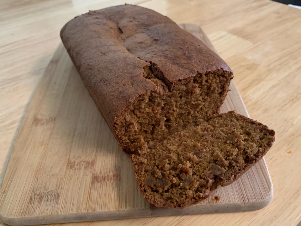 Trader joe's gluten free pumpkin loaf with a slice cut on a wooden cutting board