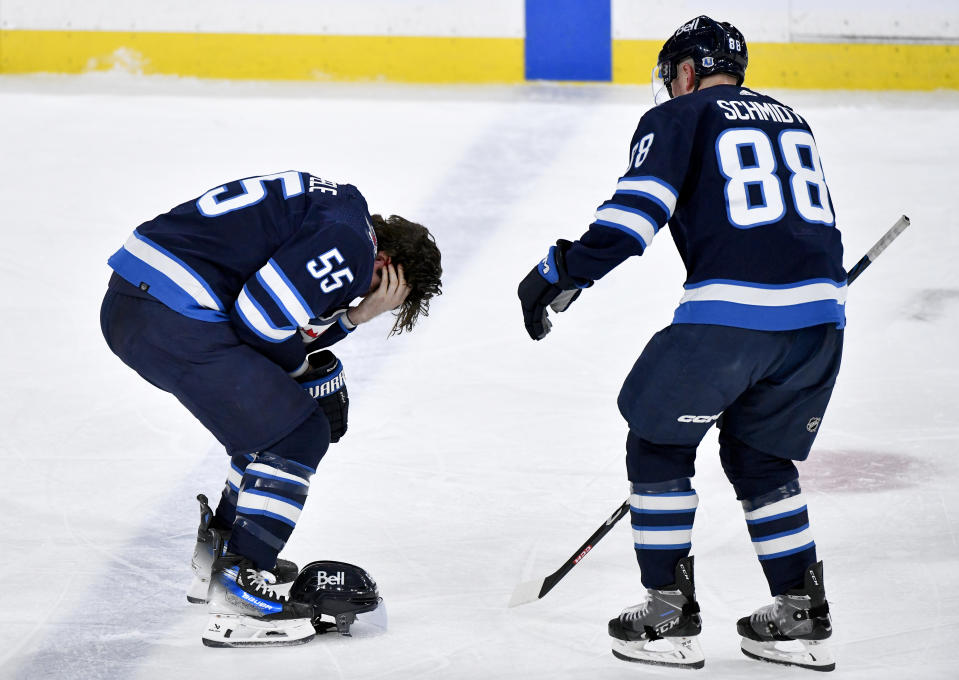 Winnipeg Jets' Mark Scheifele (55) leaves the ice after getting hit by a puck against the Columbus Blue Jackets as Nate Schmidt (88) looks on during the third period of an NHL hockey game, Tuesday Jan. 9, 2024 in Winnipeg, Manitoba.(Fred Greenslade/The Canadian Press via AP)