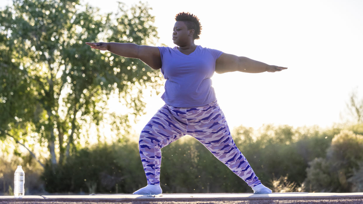  Woman holding a warrior two pose, doing yoga to improve her leg strength 