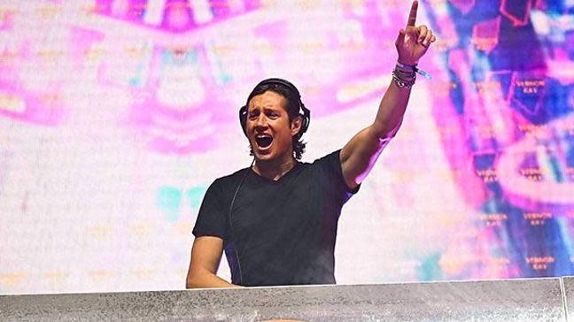 Vernon Kay behind a DJ desk with his hand in the air