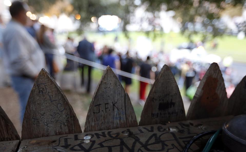 Dealey Plaza in Dallas is seen looking out over the infamous wooden picket fence at the top of the "Grassy Knoll" towards a crowd of conspiracy theorists chanting and protesting on the spot where the president was shot as people gather at the site in Dalla