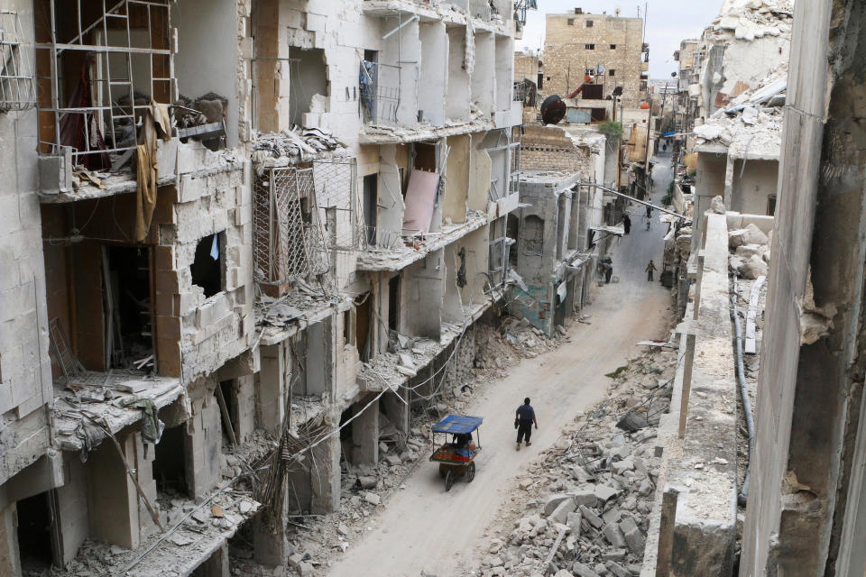 Residents walk near damaged buildings in the rebel held area of Old Aleppo, Syria on May 5, 2016.