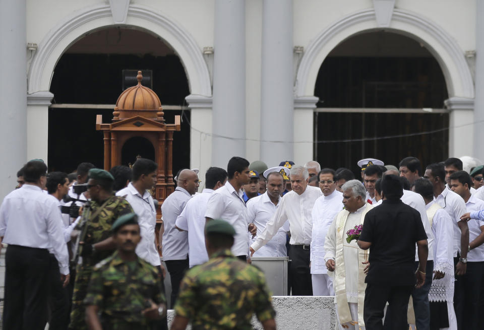 Sri Lankan President Maithripala Sirisena and Prime Minister Ranil Wickremasinghe, facing camera at right, attend a brief holly service marking the seventh day of the Easter Sunday attacks out side the exploded St. Anthony's Church in Colombo, Sri Lanka, Sunday, April 28, 2019. Sri Lanka's Catholics on Sunday awoke preparing to celebrate Mass in their homes by a televised broadcast as churches across the island shut over fears of militant attacks, a week after the Islamic State-claimed Easter suicide bombings. (AP Photo/Eranga Jayawardena)