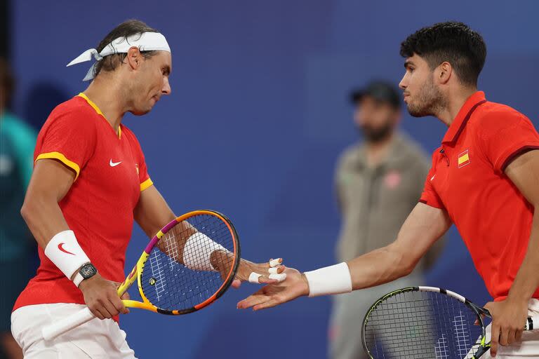 Rafael Nadal y Carlos Alcaraz se felicitan; los españoles vencieron a los argentinos Andrés Molteni y Machi González en el debut del dobles