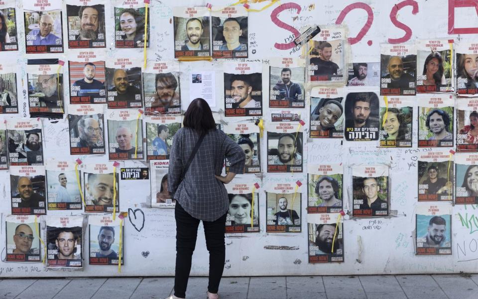 A woman  in Tel Aviv looks at a wall covered with photos of hostages held in the Gaza Strip