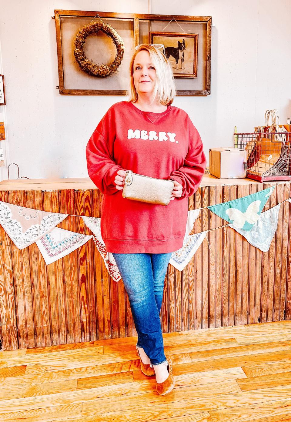 Folly Boutique’s Becky Walker with Aluminum Petunia’s Merry sweatshirt and the wildly popular and practical Jen & Co clutch that comes with a detachable strap. Fountain City, Dec. 8, 2022.