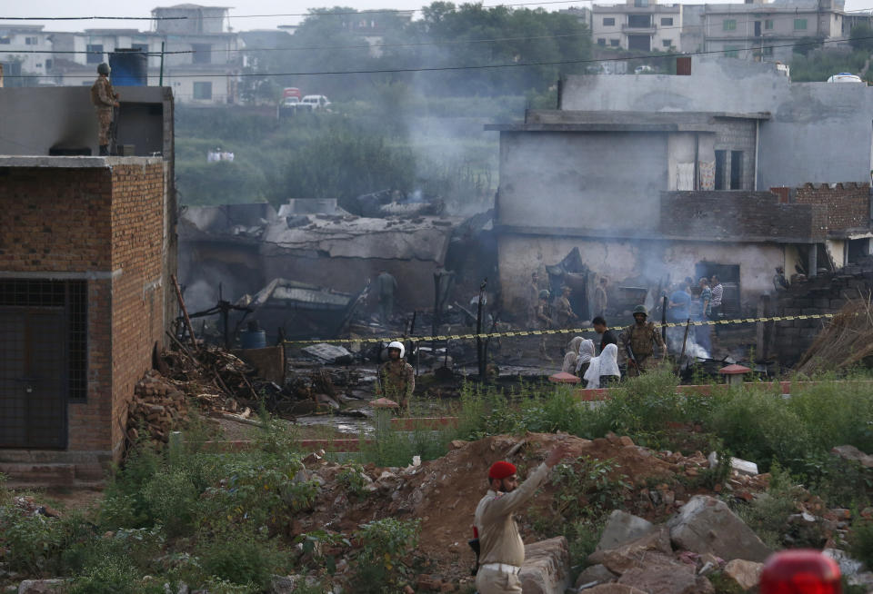 Pakistan army officials examine the site of a plane crash in Rawalpindi, Pakistan, Tuesday, July 30, 2019. A small Pakistani military plane crashed into a residential area near the garrison city of Rawalpindi before dawn, killing some people, officials said. (AP Photo/Anjum Naveed)