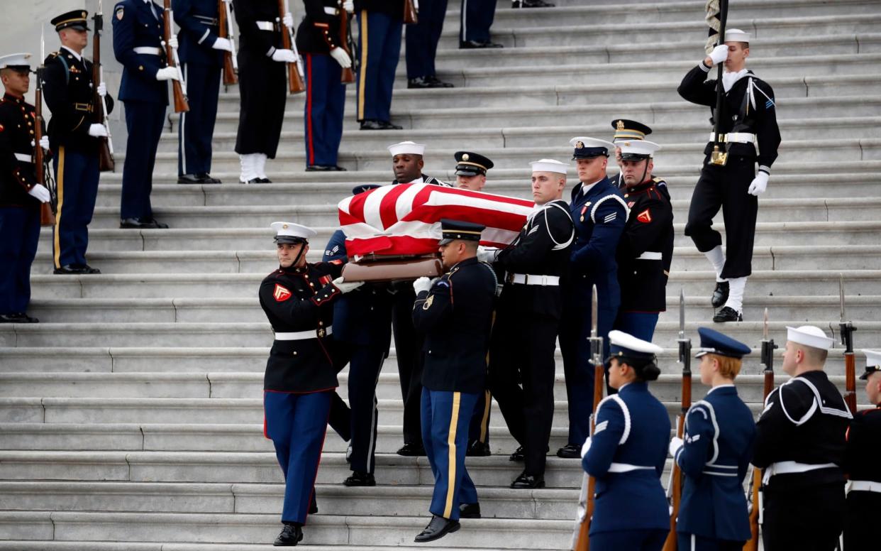 The flag-draped casket of former President George HW Bush is carried by a joint services military honour guard - Pool AP