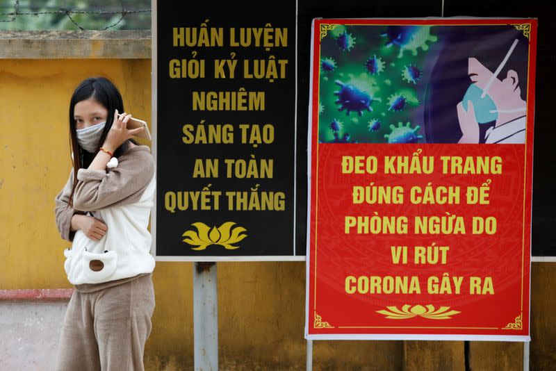 FILE PHOTO: Vietnamese woman who came back from China wears a protective mask while talking on the phone with a relative inside a quarantine area at a military base in Lang Son province