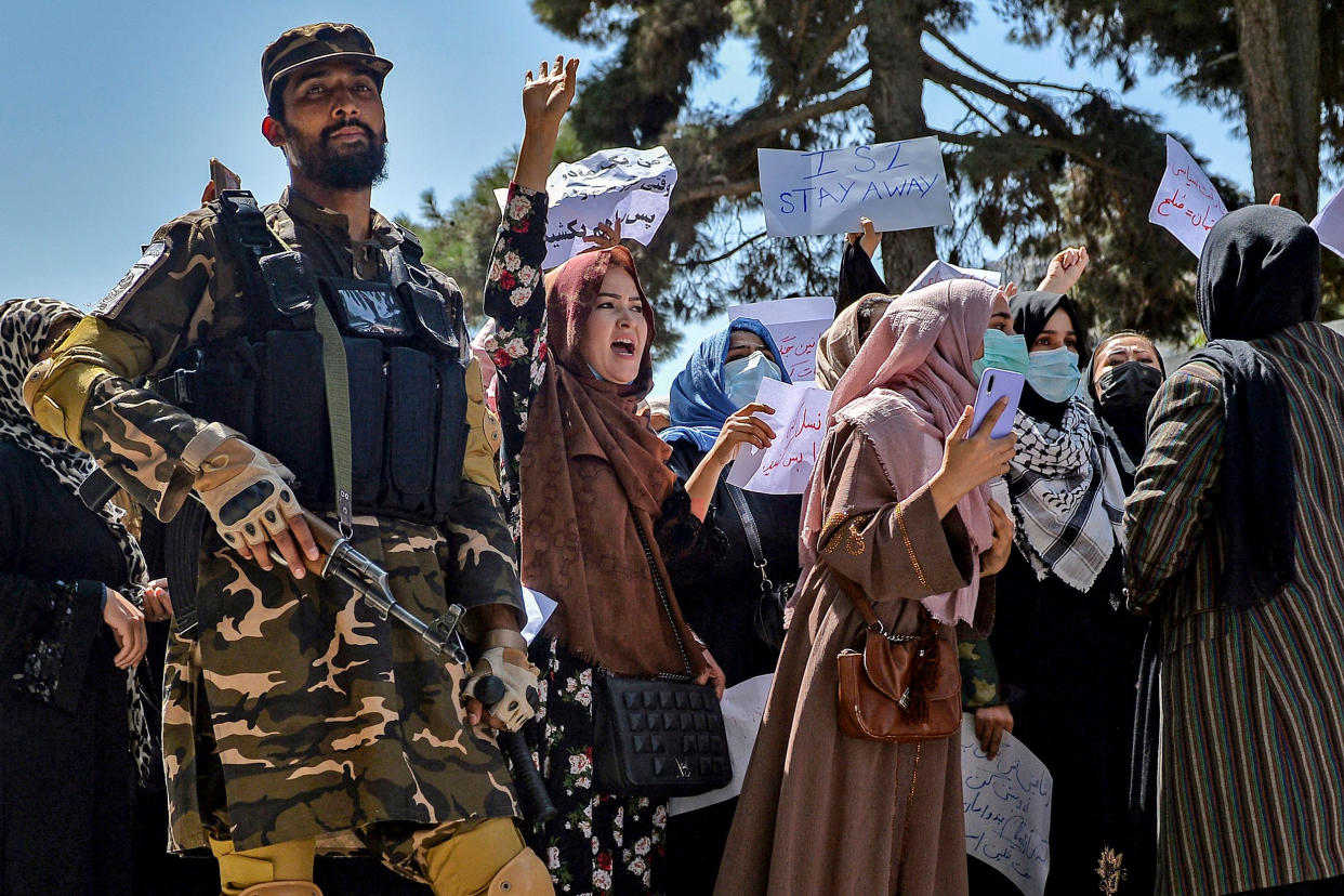 Image: A Taliban fighter stands guard as Afghan women shout slogans during a protest rally near Pakistan's embassy in Kabul on Tuesday. (Hoshang Hashimi / AFP via Getty Images)