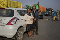 Dharam Singh Sandhu, 67, and his wife Nirmaljeet Singh Kaur, 66, stand for a photograph next to their car where they are spending nights parked near the site of a protest against new farming laws, at the Delhi-Haryana state border, India, Tuesday, Dec. 1, 2020. In the morning, they share breakfast at a makeshift soup kitchen. The latter part of the day is spent taking part in the demonstrations. "Our land is our mother. If we can't protect it then we have no right to live," Sandhu said about the protests. "Our country is like a bunch of flowers, but Modi wants it to be of the same color. He has no right to do that. I am here to protest against that mindset," Kaur said. (AP Photo/Altaf Qadri)