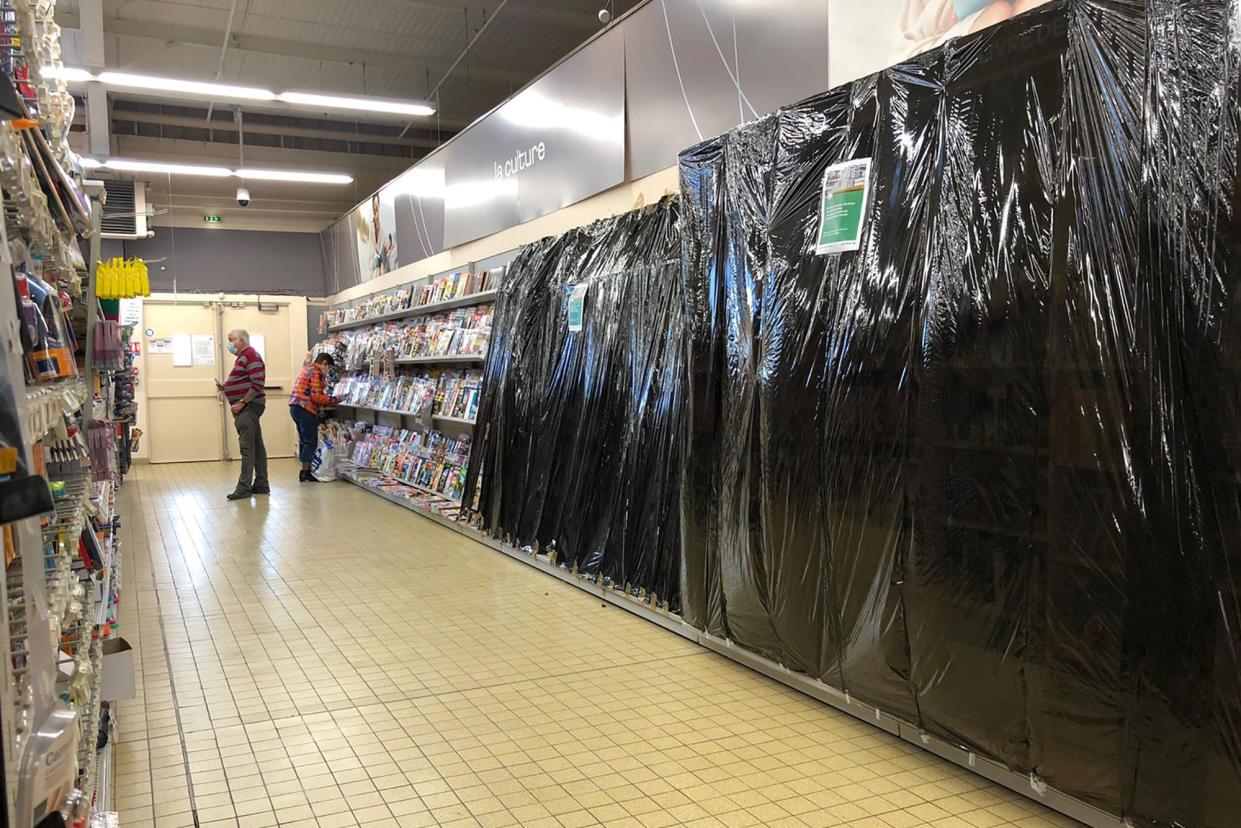 A customer picks up a magazine in a supermarket in Gex, eastern France, Monday, Nov. 2, 2020. French supermarkets won't be allowed to sell books, make-up, clothes and other goods considered as not essential as smaller businesses have been forced to shut down amid virus lockdown, the French government said Monday. Bookshops owners and others have been complaining about unfair competition as they are already struggling to survive.