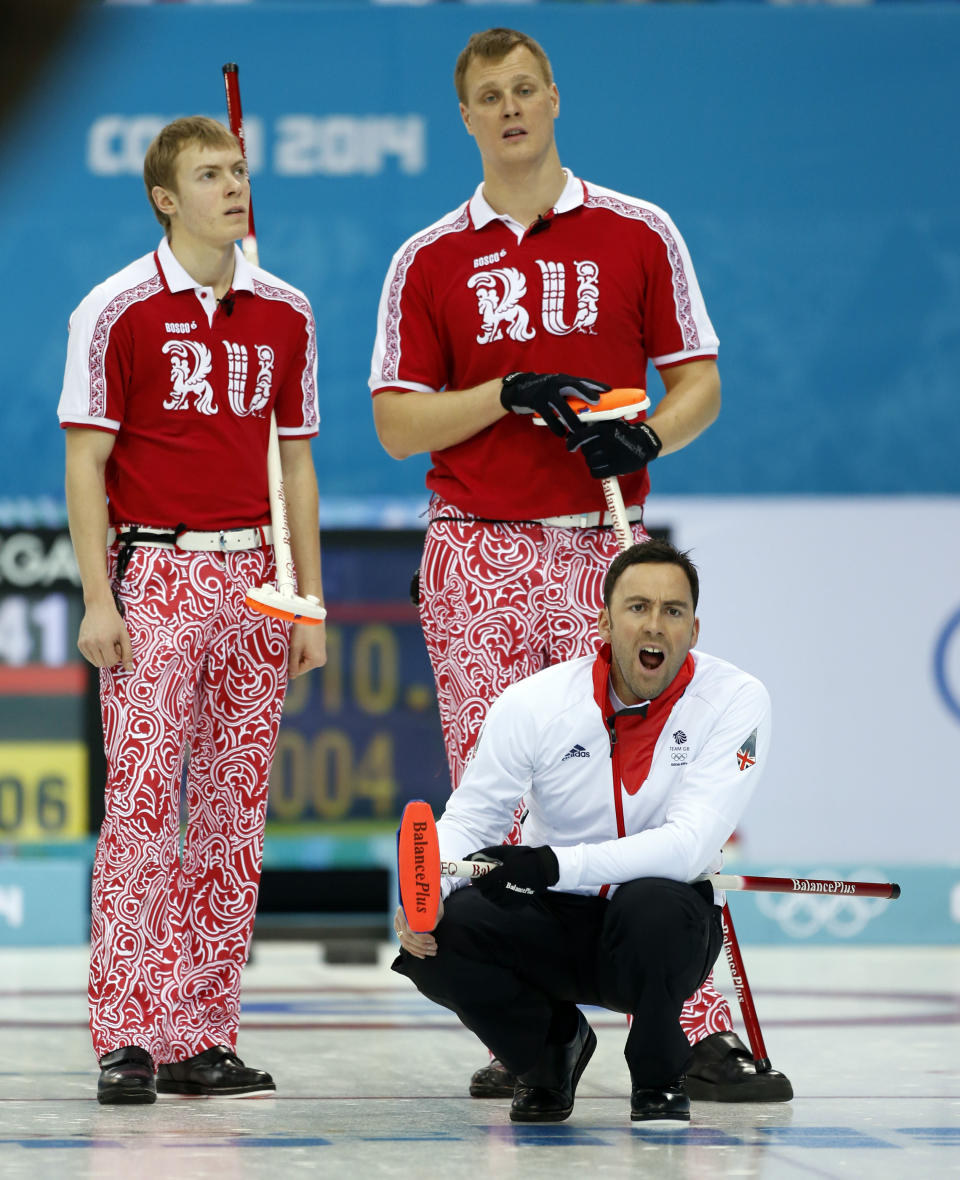 Great Britain skip David Murdoch, lower right, shouts instructions after delivering the rock in men's curling competition against Russia at the 2014 Winter Olympics, Monday, Feb. 10, 2014, in Sochi, Russia. Russia's Evgeny Arkhipov, left, and Petr Dron stand behind Murdoch. (AP Photo/Robert F. Bukaty)