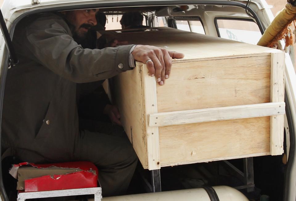 A relative sits in a van with the casket of a victim who was killed in a bomb attack, to be transported from a hospital morgue to his home in Rawalpindi