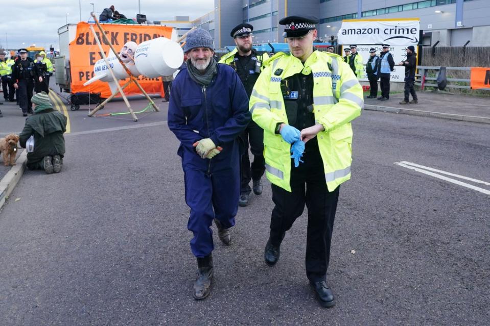 An activist from Extinction Rebellion is led away by police as they block the entrance to the Amazon fulfilment centre in Tilbury, Essex (Ian West/PA) (PA Wire)