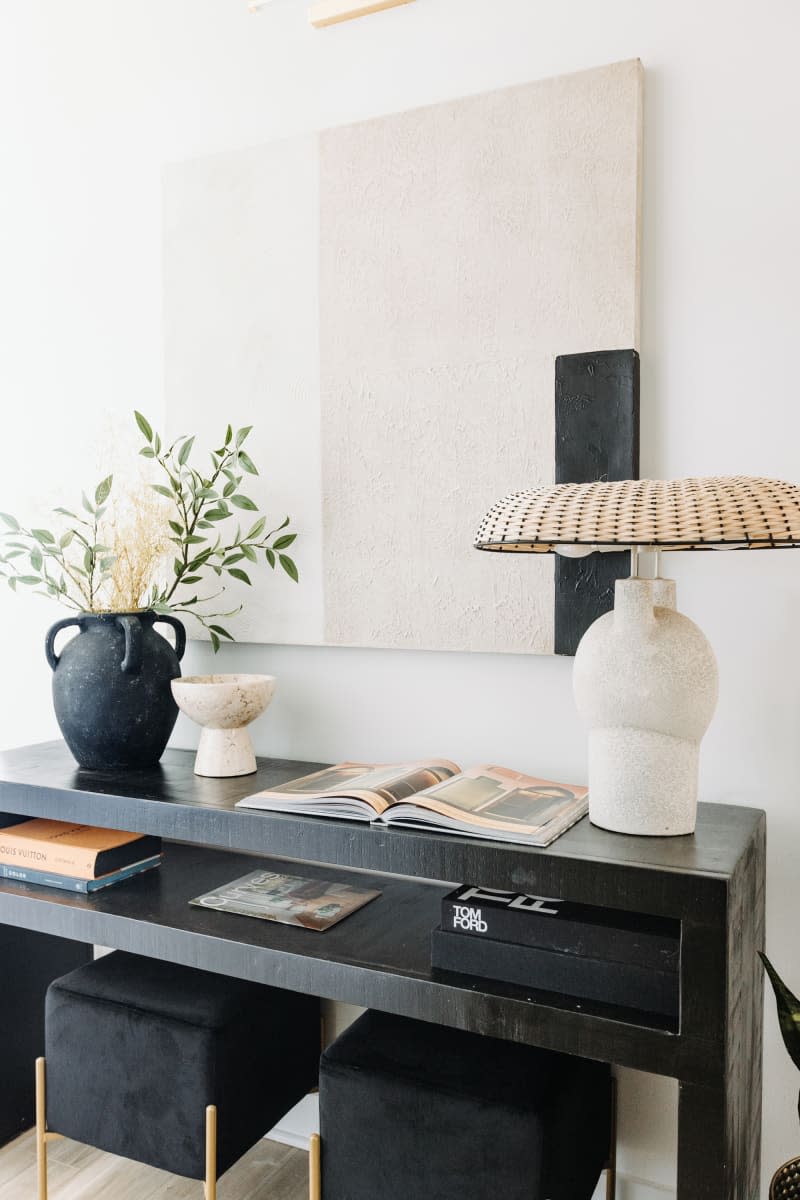 detail of black console table with 2 stools, lamp, artwork