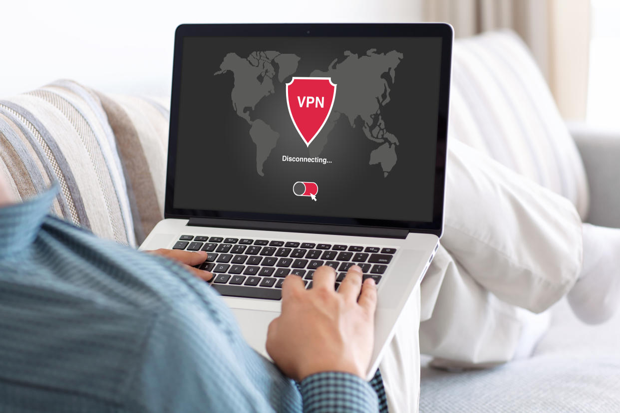  Man holding laptop with VPN app. 