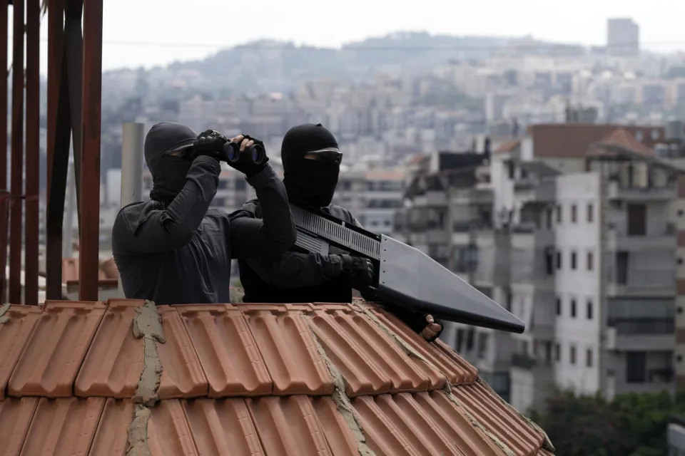 Hezbollah fighters stand guard as Hezbollah leader Sheikh Hassan Nasrallah speaks on a screen in Beirut.