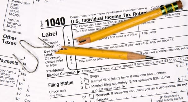 Tax forms a broken pencil and a twisted paper clip tell the story of a frustrated person