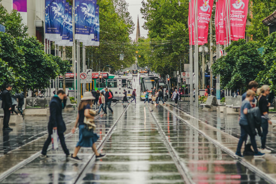 Melbourne, Victoria, Australia, March 31, 2019: Bourke Street in the centre of the city  is wet from recent rain while pedestrians and trams share the road space.