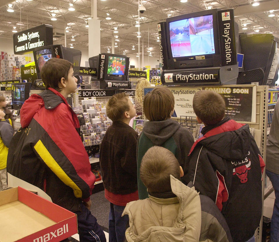 A bunch of kids playing the original PlayStation in a display at a Best Buy