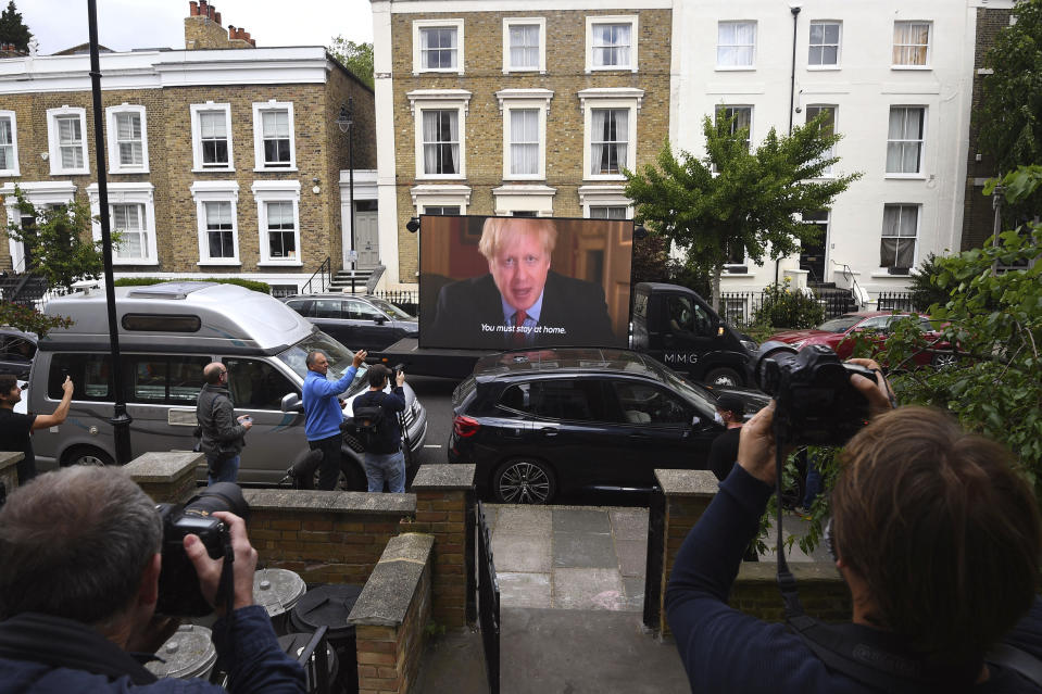 Political campaign group Led By Donkeys transport a screen showing a prerecorded video link of Britain's Boris Johnson delivering a statement, outside the home of his senior aide Dominic Cummings, in London, Sunday May 24, 2020. Several lawmakers from Britain’s governing Conservative Party have joined opposition calls for Johnson’s top aide to be fired for flouting lockdown rules. Dominic Cummings traveled 250 miles (400 kilometers) to his parents’ home with his wife and son as he was coming down with COVID-19 at the end of March. Britain's lockdown, which began March 23, stipulated that people should remain at their primary residence and not visit relatives. (Victoria Jones/PA via AP)