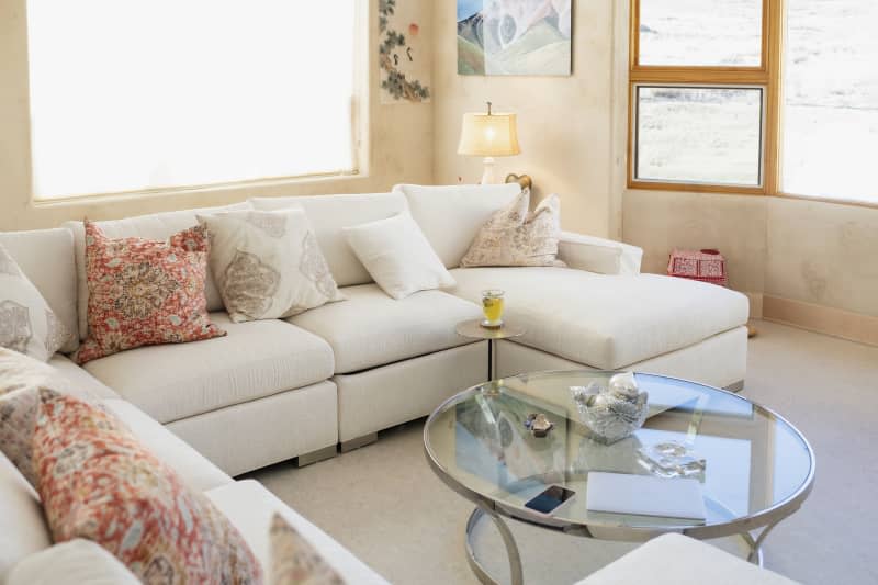 View of residential living room with white sofa, cup of tea, laptop and phone