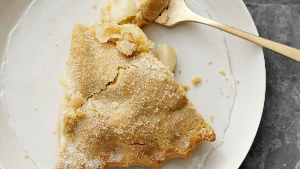 a slice of double crust all american apple pie on a white plate with a gold fork