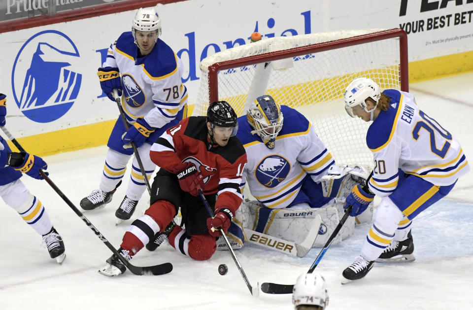 New Jersey Devils left wing Andreas Johnsson (11) attempts to get his stick on the puck as Buffalo Sabres goaltender Linus Ullmark (35) and center Cody Eakin (20) defend during the first period of an NHL hockey game Tuesday, Feb. 23, 2021, in Newark, N.J. (AP Photo/Bill Kostroun)