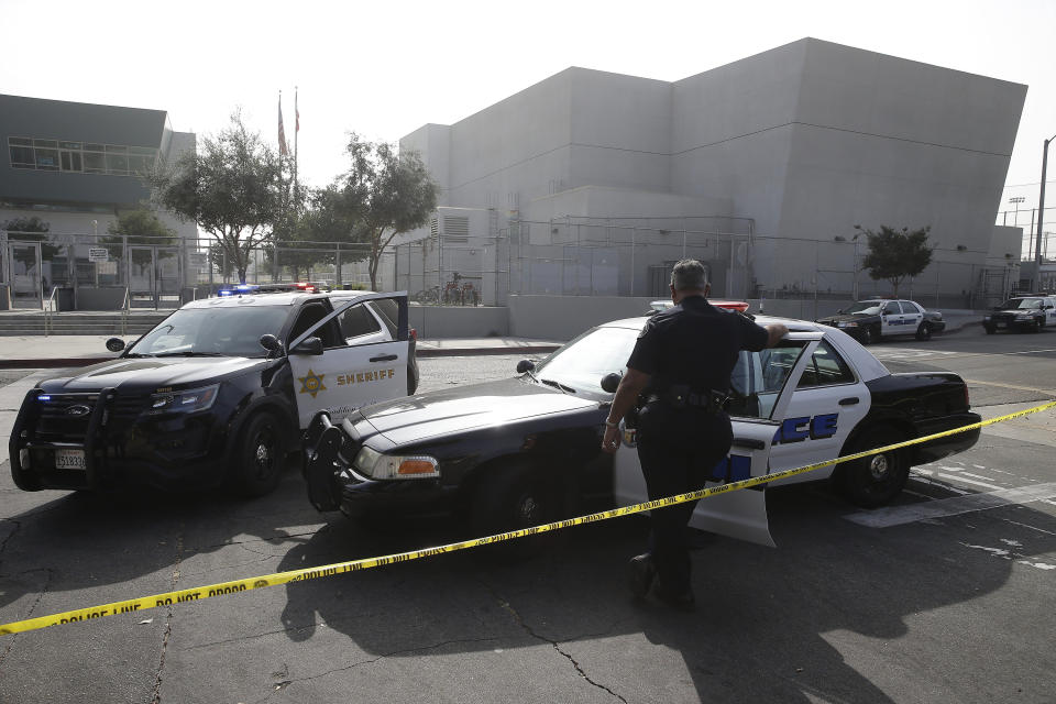 FILE - Los Angeles Sheriffs officers and Los Angeles Unified School District police officers guard the campus of Esteban Torres High School in unincorporated East Los Angeles, after a sheriff's deputy fatally shot a man wielding a sword, after he had climbed over the fence to get onto the school grounds Wednesday, Nov. 13, 2019. On Tuesday, June 30, 2020, the Los Angeles Unified School District voted an immediate 35% cut to the budget of its school police. (AP Photo/Damian Dovarganes, File)