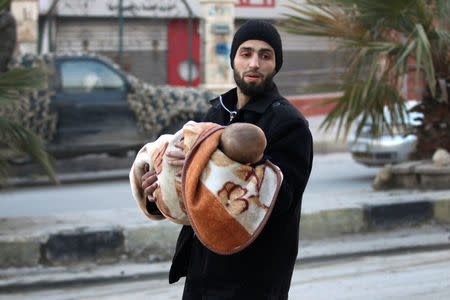 A man carries a child as he flees deeper into the remaining rebel-held areas of Aleppo, Syria. REUTERS/Abdalrhman Ismail