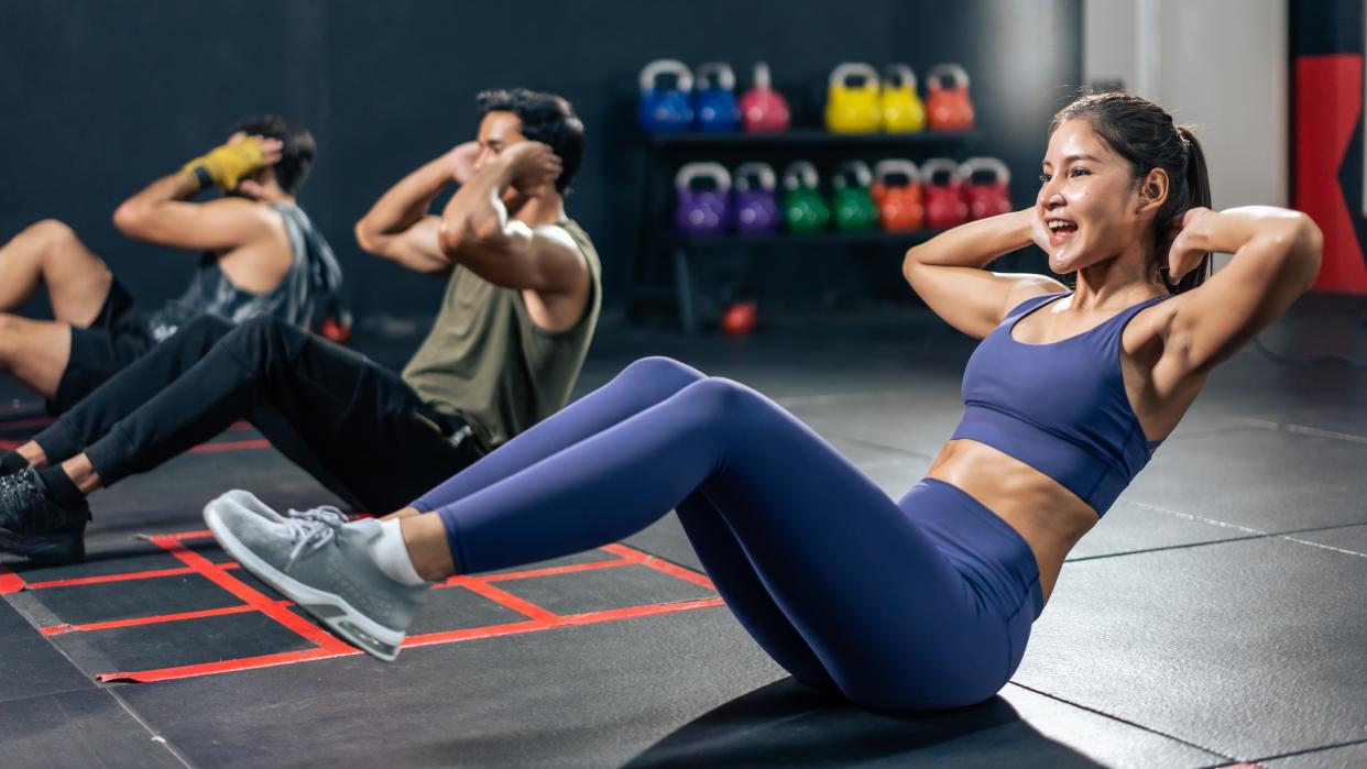  a photo of a woman doing the v-sit exercise in the gym 