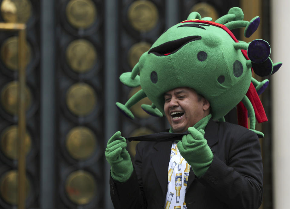 A street artist costumed as the new coronavirus laughs during a protest demanding the resumption of economic activities after not being able to earn a living since March because of the restrictions to curb the spread of COVID-19 in Mexico City, Thursday, June 11, 2020. Mexico’s industrial activity plunged by nearly 30% in April compared to a year earlier as the economy ground to a halt under measures aimed at slowing the spread of the virus. (AP Photo/Fernando Llano)