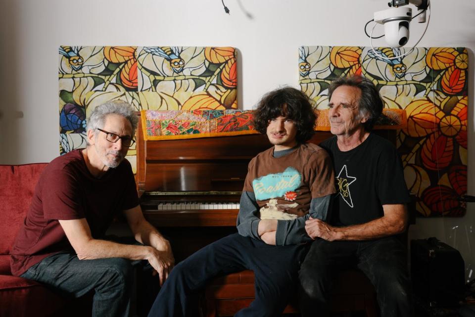 Two adults and a teenager sit in front of a piano