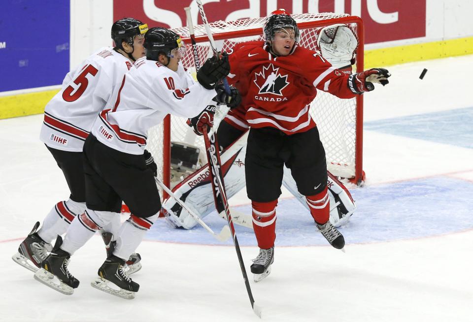 Canada's Josh Morrissey (R) knocks the puck away from Switzerland's Dario Simion (L) and Vincent Praplan during the third period of their IIHF World Junior Championship ice hockey game in Malmo, Sweden, January 2, 2014. REUTERS/Alexander Demianchuk (SWEDEN - Tags: SPORT ICE HOCKEY)