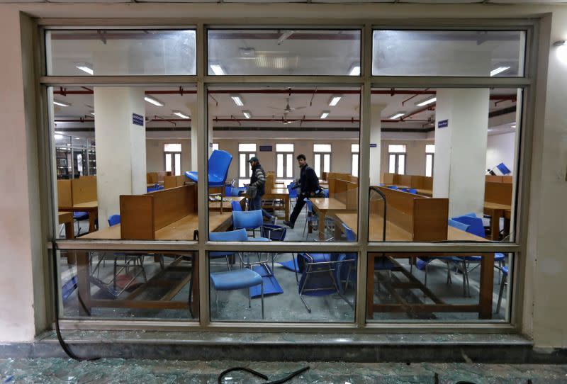 People walk inside a partially damaged library of the Jamia Millia Islamia university in New Delhi