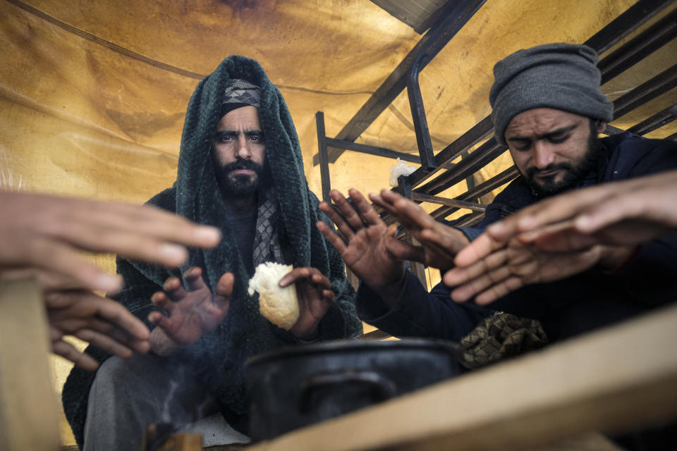 Migrants warm their hands above a fire at the Lipa camp, outside Bihac, Bosnia, Monday, Jan. 11, 2021. Aid workers say migrants staying at a camp in northwestern Bosnia have complained or respiratory and skin diseases after spending days in make-shift tents and containers amid freezing weather and snow blizzards. Most of the hundreds of migrants at the Lipa facility near Bosnia's border with Croatia on Monday have been accommodated in heated military tents following days of uncertainty after a fire gutted most of the camp on Dec. 23. (AP Photo/Kemal Softic)